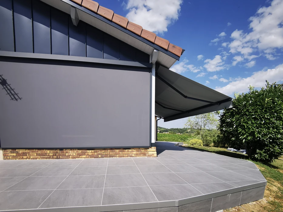 Terrasse extérieure moderne avec store banne déployé gris anthracite fixé sur façade contemporaine