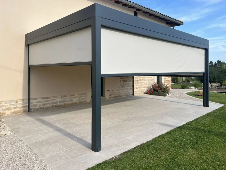 Terrasse extérieure couverte d'une pergola moderne avec store enrouleur blanc partiellement déployé