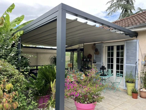 Terrasse extérieure résidentielle avec pergola bioclimatique à lames orientables installée contre façade