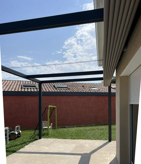 Terrasse extérieure résidentielle avec pergola bioclimatique à lames orientables et panneaux de verre transparent
