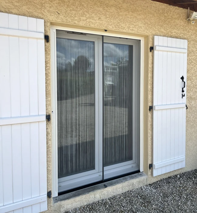 Façade extérieure d'habitation avec porte-fenêtre coulissante à double vantail en PVC blanc