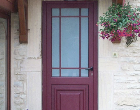Entrée extérieure d'habitation avec porte d'entrée en bois rouge bordeaux à panneaux, équipée d'un vitrage à petits bois dans la partie haute