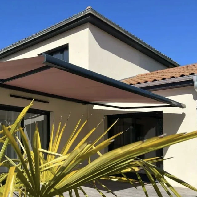 Maison contemporaine avec terrasse extérieure aménagée, table et chaises en bois sous store banne rétractable