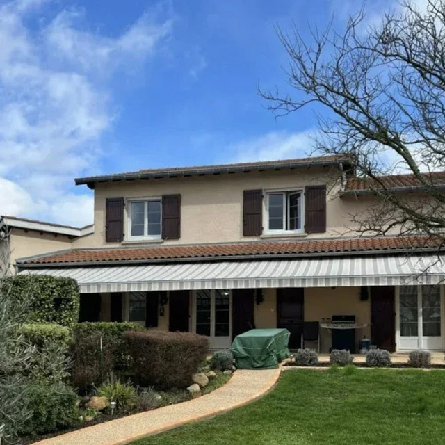 Terrasse couverte avec store banne rétractable beige déployé, structure métallique noire