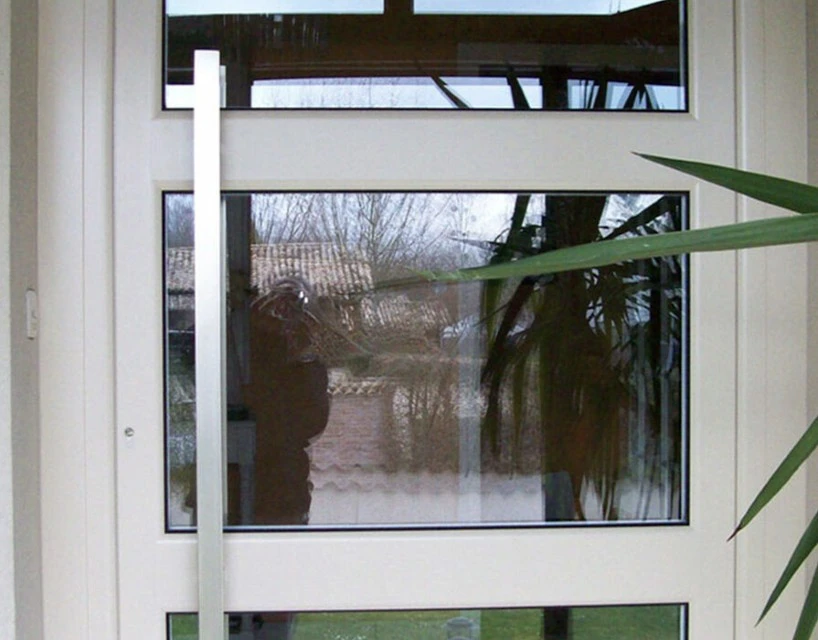 Façade extérieure d'une maison traditionnelle en pierre calcaire avec volets battants bordeaux, porte d'entrée vitrée assortie et véranda attenante
