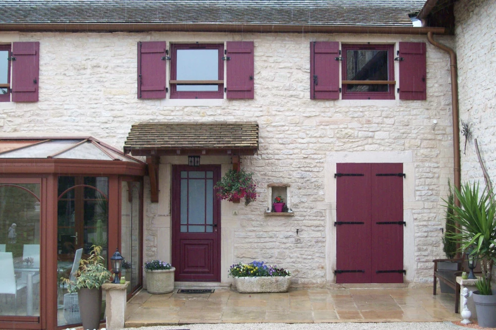 Intérieur lumineux avec grandes fenêtres à croisillons blancs donnant sur cour pavée et bâtiments anciens
