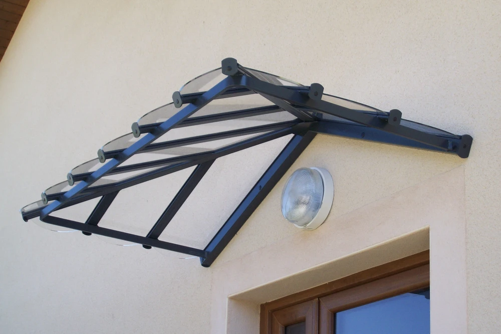 Terrasse extérieure couverte d'une pergola moderne avec store enrouleur blanc partiellement déployé