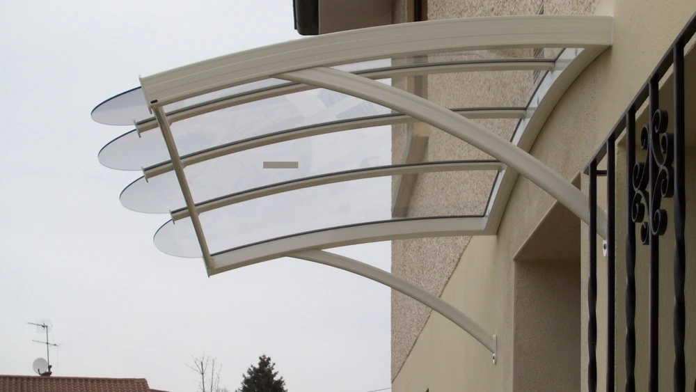 Terrasse extérieure couverte d'une pergola moderne avec store enrouleur blanc partiellement déployé