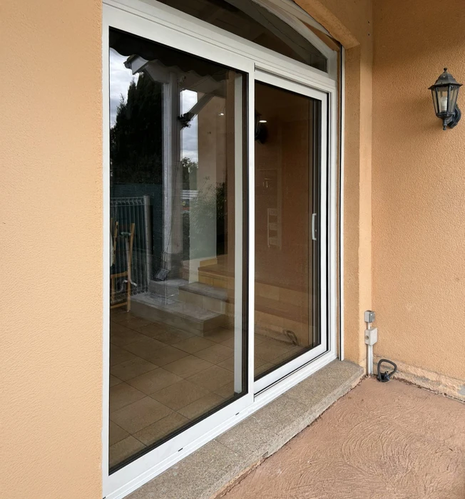 Façade extérieure résidentielle avec porte d'entrée double battant blanche et porte de garage enroulable blanche