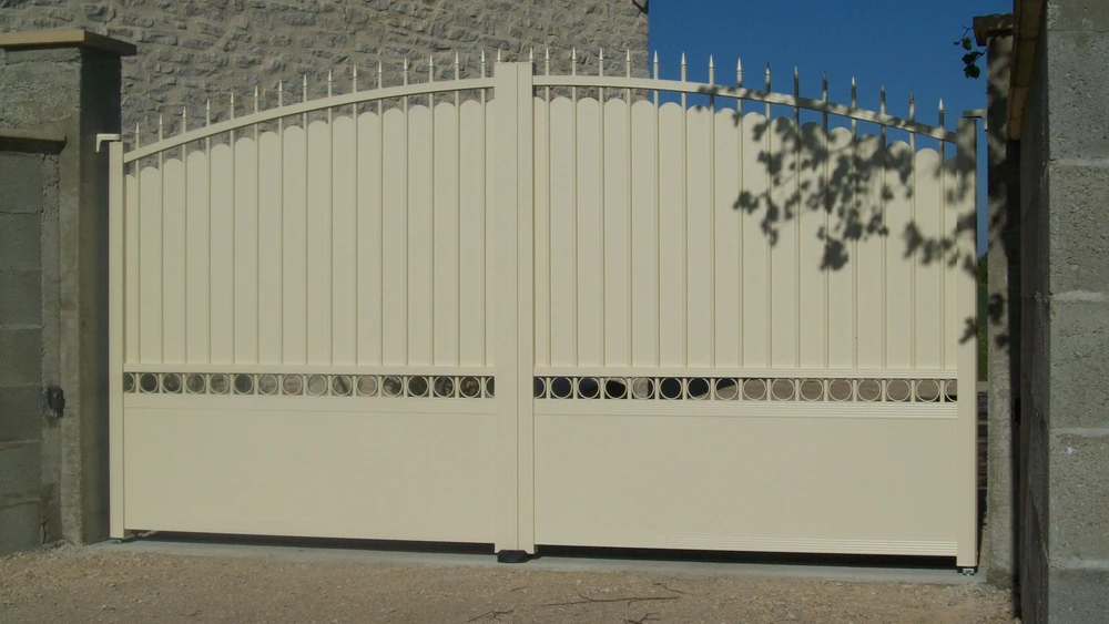 Portail métallique noir automatique ouvert sur route asphaltée, vignoble en arrière-plan