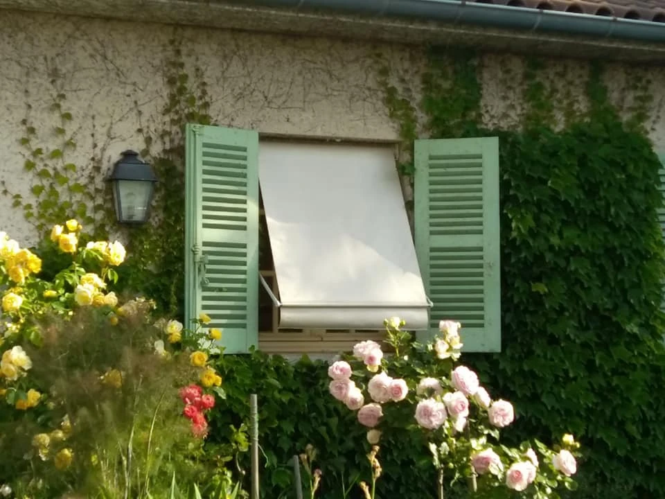 Terrasse couverte moderne avec pergola bioclimatique à lames orientables et stores extérieurs beiges déroulés