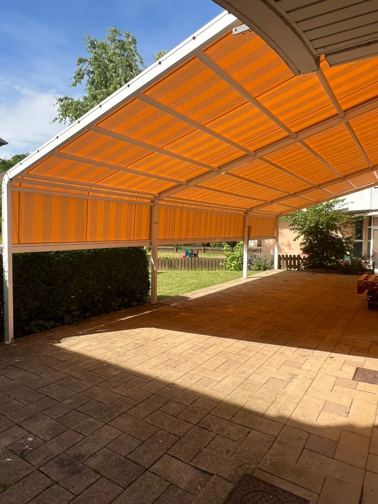 Terrasse couverte moderne avec pergola bioclimatique à lames orientables et stores extérieurs beiges déroulés