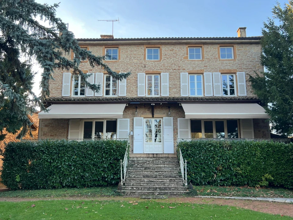 Terrasse couverte moderne avec pergola bioclimatique à lames orientables et stores extérieurs beiges déroulés