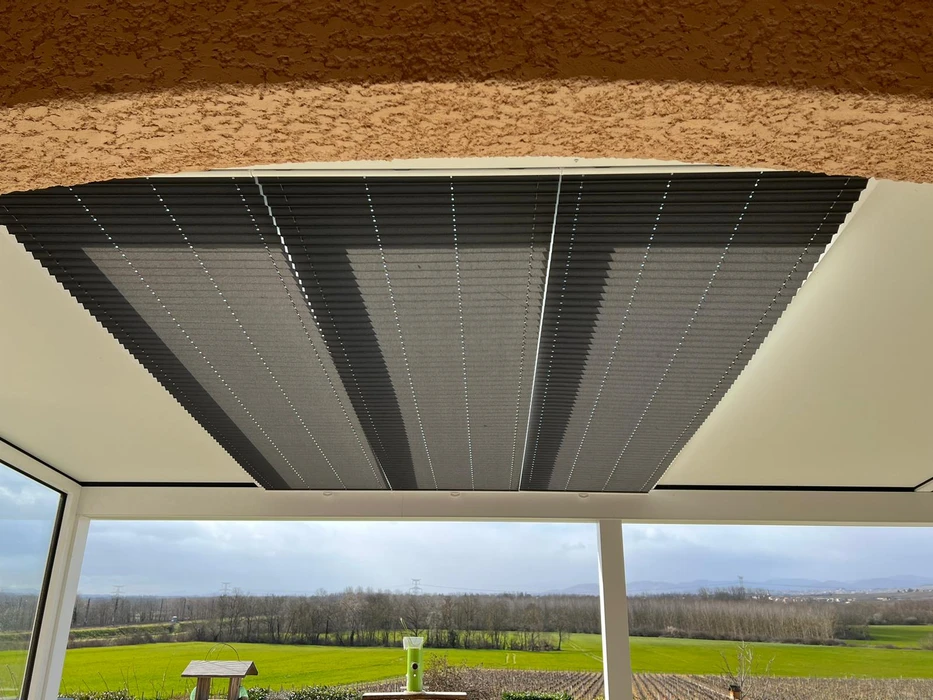 Terrasse couverte moderne avec pergola bioclimatique à lames orientables et stores extérieurs beiges déroulés