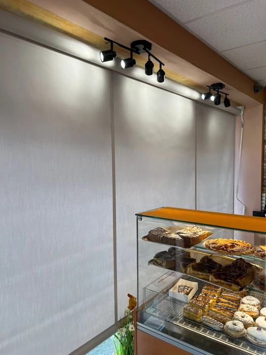 Terrasse couverte moderne avec pergola bioclimatique à lames orientables et stores extérieurs beiges déroulés