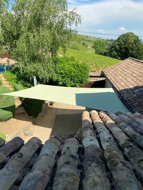 Terrasse extérieure avec store banne beige déployé offrant protection solaire au-dessus d'une balustrade métallique ornementée